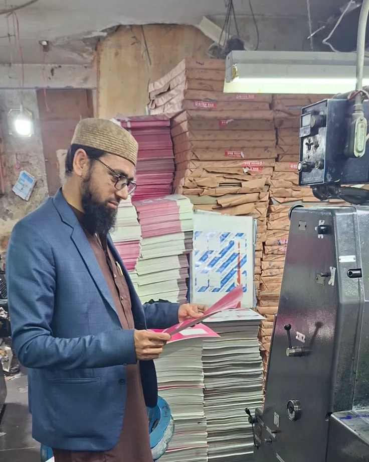 Muhammad Yaseen checking a freshly printed sheet at the offset press in our Lahore factory